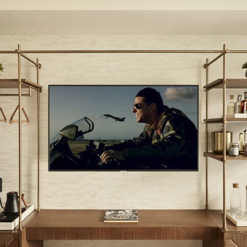 The image shows a modern room with a TV displaying a motorcycle scene. Shelves hold hangers, a robe, drinks, and decor items on each side.